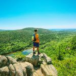 man standing on an outcrop in the mountains