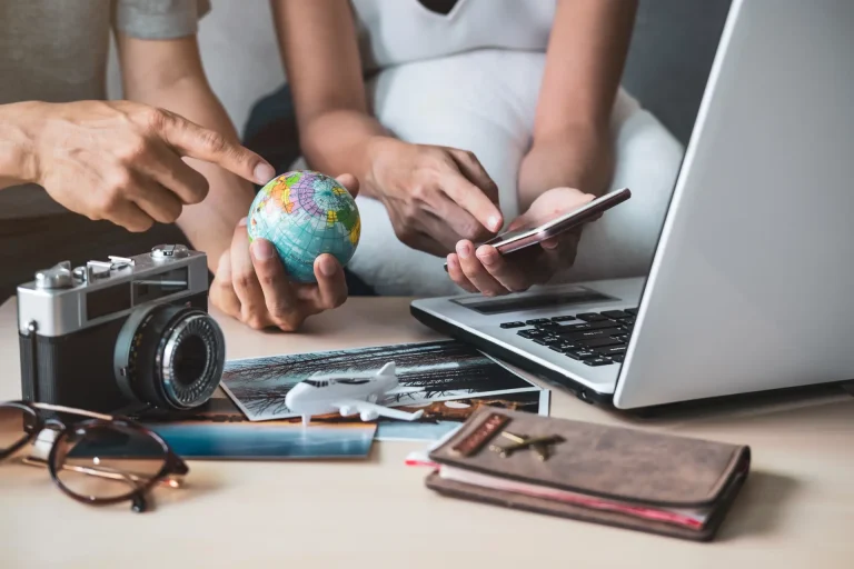 couple planning vacation with a laptop, small ,globe, camera and plane showing